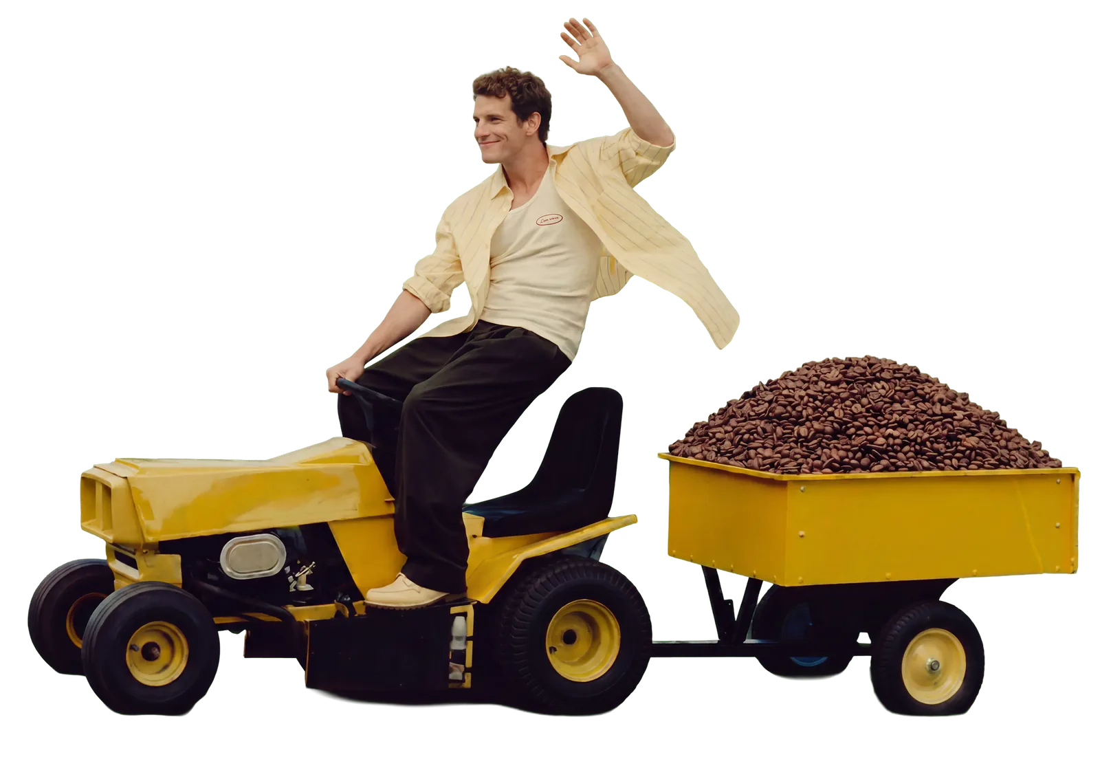 A man waving from a toy tractor towing a trailer of coffee beans